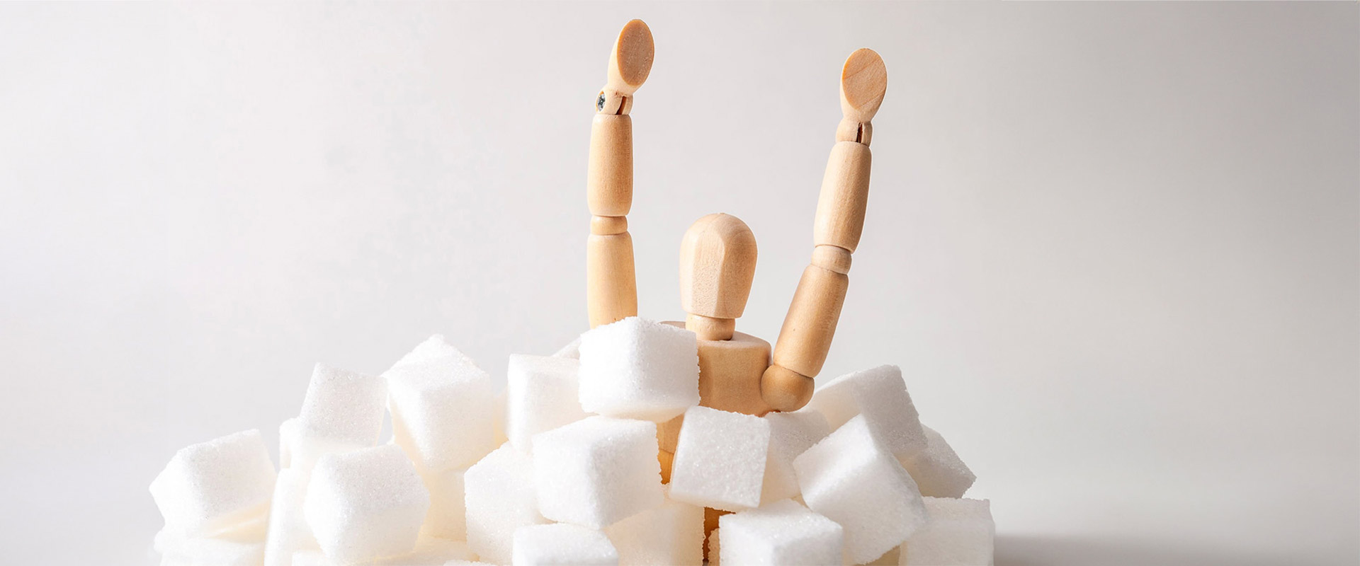 Holzfigur steht in einem Haufen aus Zuckerwürfeln mit erhobenen Armen.